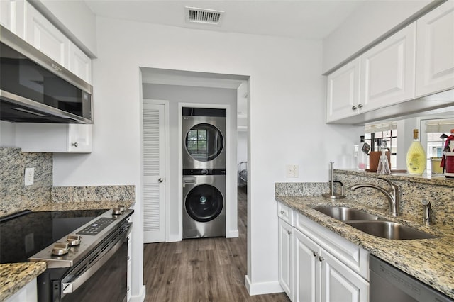 kitchen with sink, white cabinets, stacked washer / drying machine, and stainless steel appliances