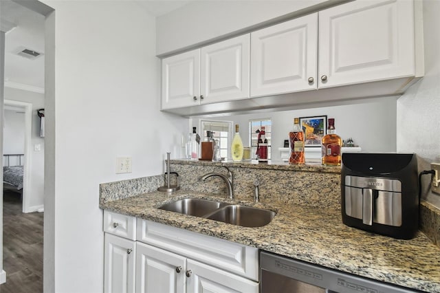 kitchen with white cabinets, dishwasher, sink, and light stone counters