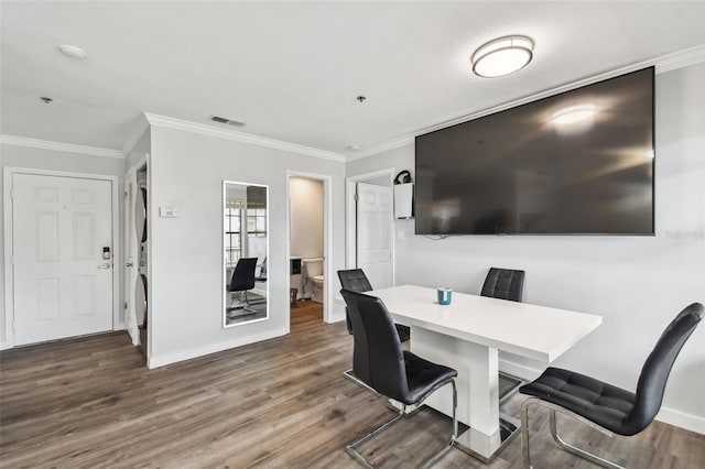 dining room featuring crown molding, stacked washer / dryer, and hardwood / wood-style flooring