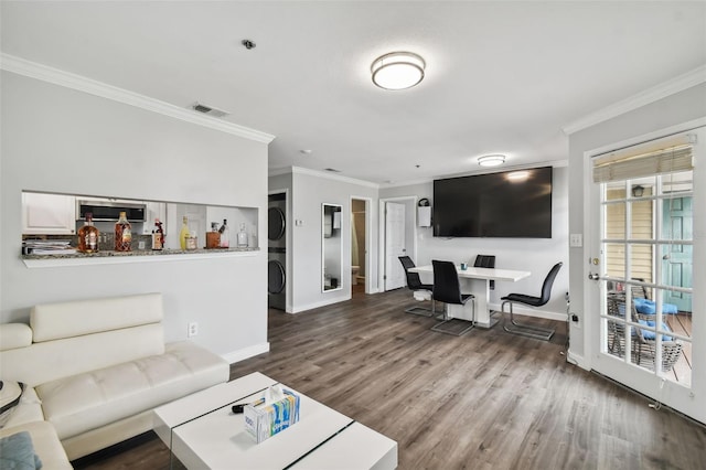 living room with stacked washer / dryer, dark wood-type flooring, and crown molding