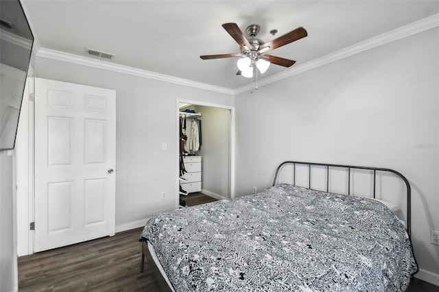 bedroom with a spacious closet, ceiling fan, a closet, dark hardwood / wood-style flooring, and ornamental molding