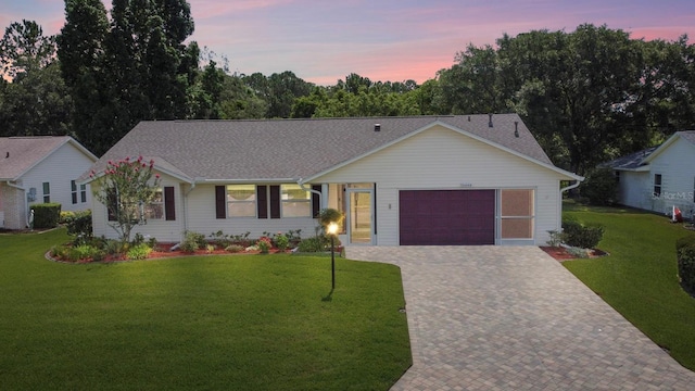 ranch-style house with a garage and a yard