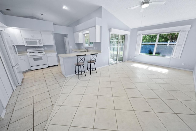 kitchen with a kitchen bar, vaulted ceiling, kitchen peninsula, white appliances, and white cabinets