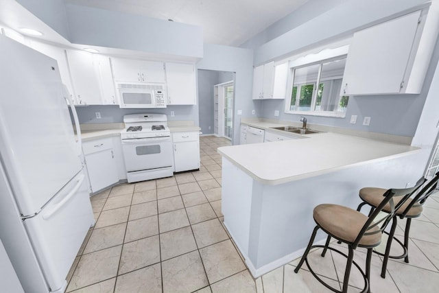 kitchen with sink, white appliances, white cabinets, a kitchen bar, and kitchen peninsula