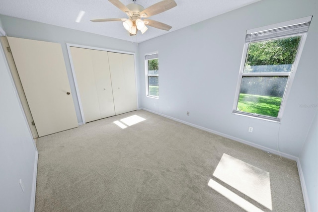 unfurnished bedroom featuring light carpet, a closet, and ceiling fan