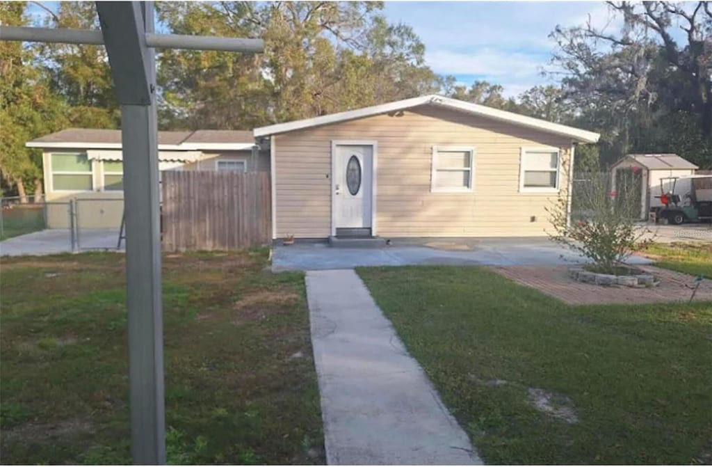 view of front of house featuring a front lawn and a storage shed