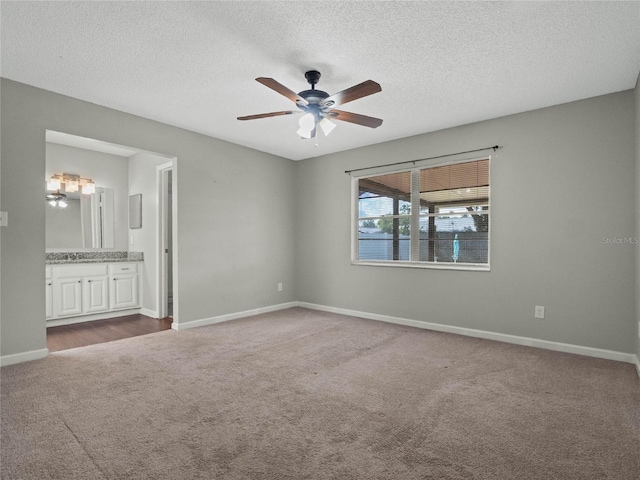 unfurnished bedroom with light carpet, ceiling fan, a textured ceiling, and connected bathroom