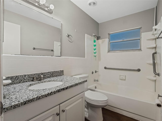 full bathroom featuring hardwood / wood-style floors, vanity, shower / bath combination, tile walls, and toilet