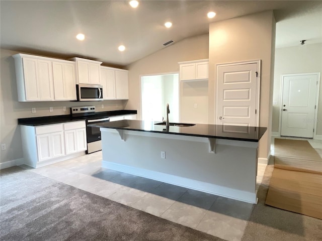 kitchen featuring white cabinets, stainless steel appliances, an island with sink, sink, and a breakfast bar area