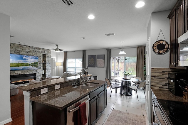 kitchen with a textured ceiling, appliances with stainless steel finishes, dark brown cabinetry, and sink