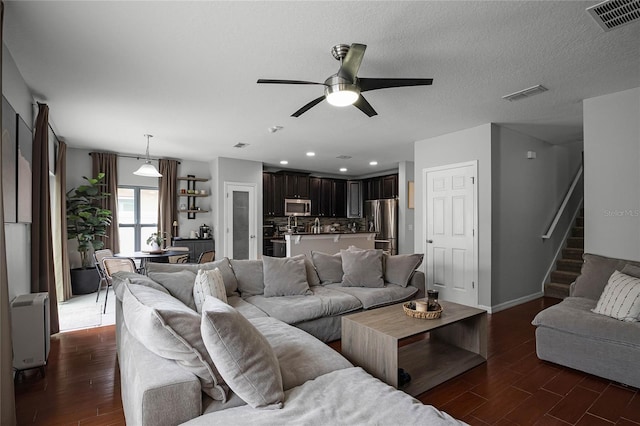 living room with ceiling fan, dark wood-type flooring, and a textured ceiling