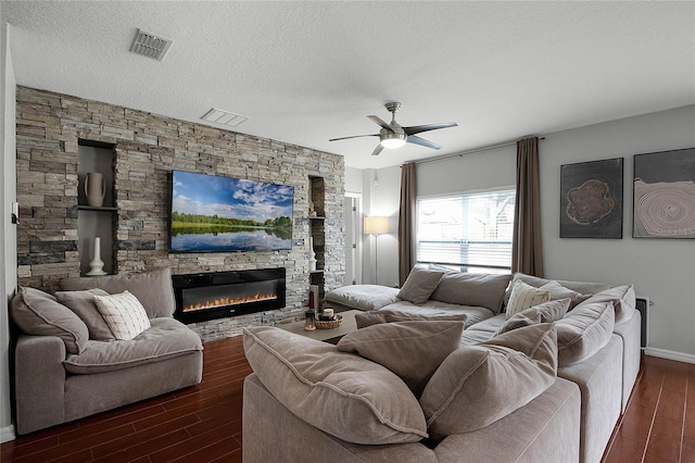 living room with ceiling fan, a textured ceiling, and a fireplace