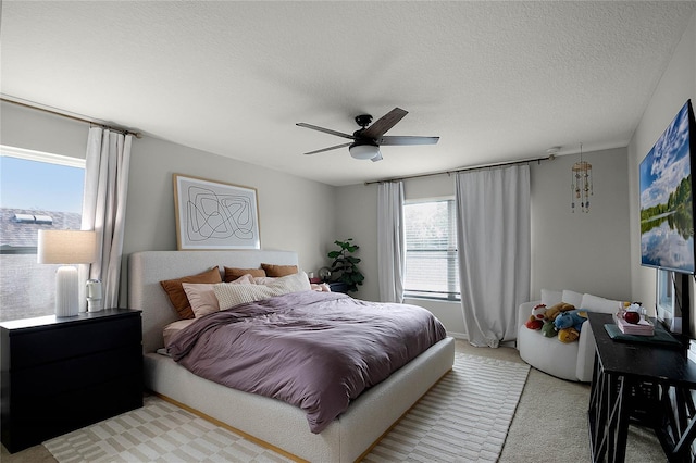 carpeted bedroom with ceiling fan and a textured ceiling