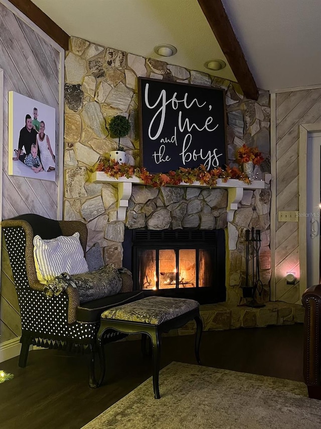 living area with beam ceiling, a fireplace, and wooden walls