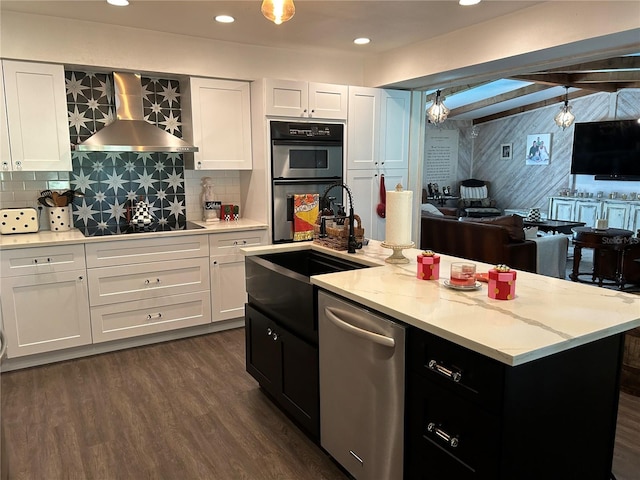 kitchen with white cabinets, stainless steel appliances, a kitchen island with sink, and wall chimney range hood