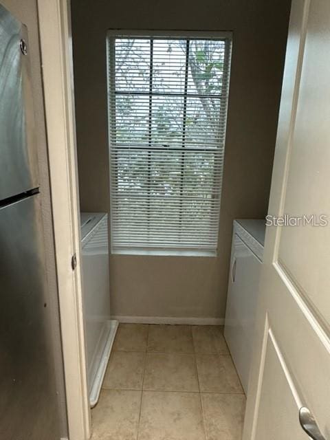 washroom with independent washer and dryer and light tile patterned flooring