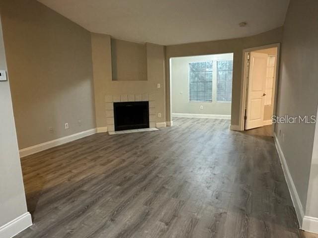 unfurnished living room with a tile fireplace and dark wood-type flooring