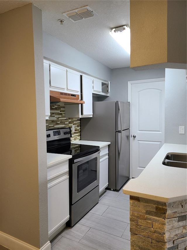 kitchen featuring sink, tasteful backsplash, white cabinetry, a textured ceiling, and stainless steel appliances