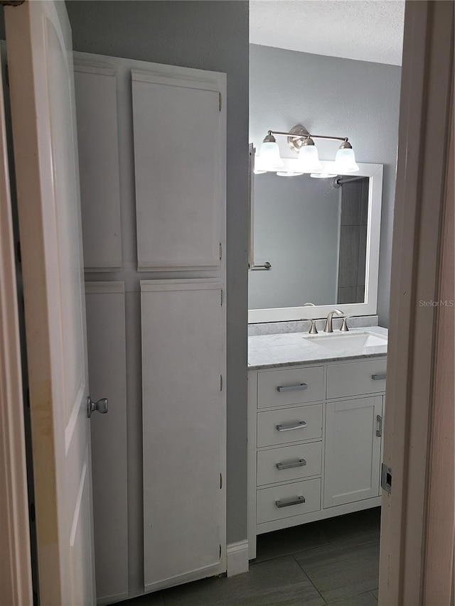 bathroom with a textured ceiling, tile patterned floors, and vanity