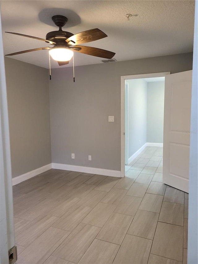 unfurnished room with ceiling fan and a textured ceiling