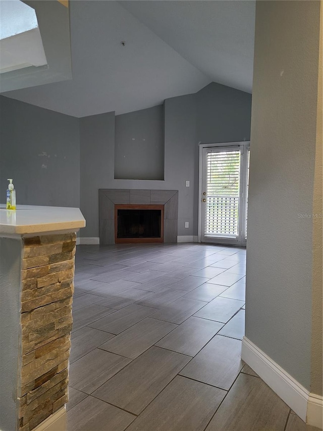 unfurnished living room featuring lofted ceiling and a stone fireplace