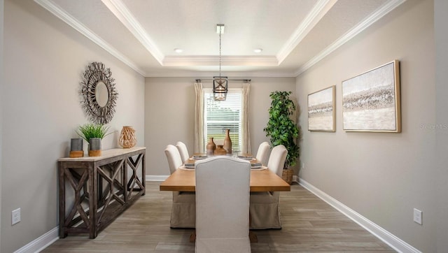 dining area featuring hardwood / wood-style flooring, a tray ceiling, and crown molding