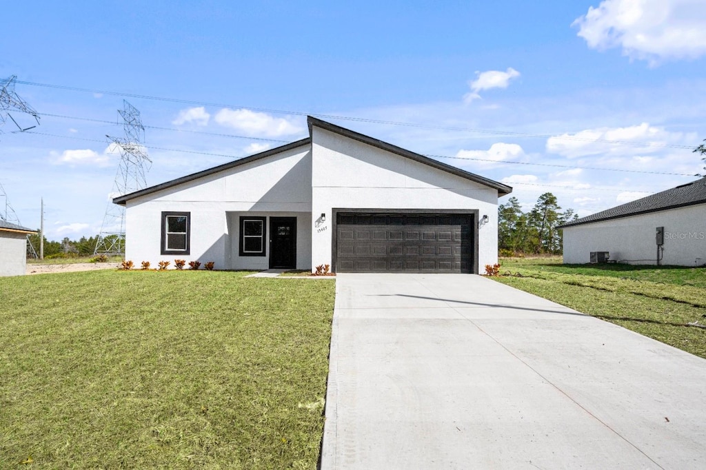 view of front of home featuring a garage, a front lawn, and central air condition unit