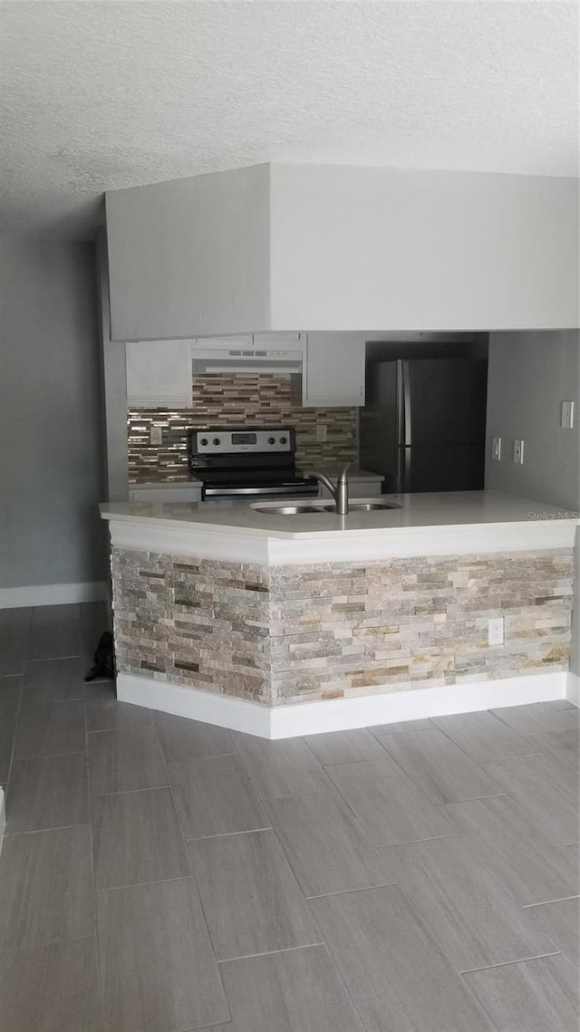 kitchen featuring black refrigerator, sink, a textured ceiling, and stainless steel electric stove