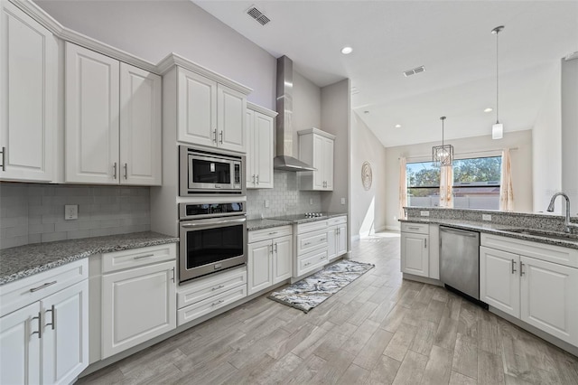 kitchen with sink, white cabinets, light hardwood / wood-style floors, stainless steel appliances, and wall chimney range hood