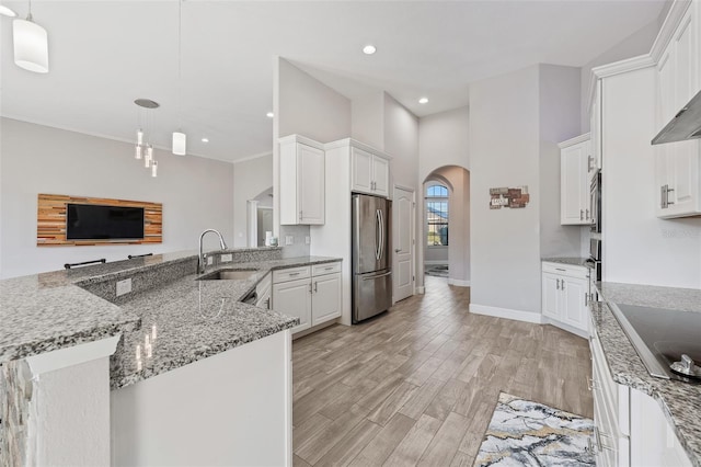 kitchen featuring kitchen peninsula, white cabinets, stainless steel refrigerator, and decorative light fixtures