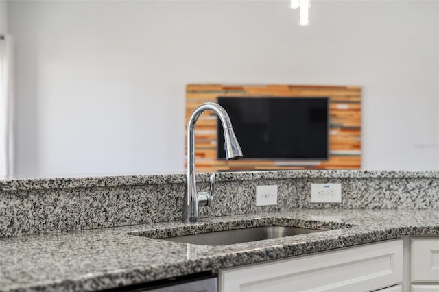 room details with white cabinetry, backsplash, sink, and dark stone countertops