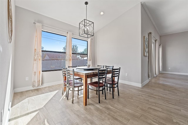 dining room with an inviting chandelier, lofted ceiling, ornamental molding, and light wood-type flooring