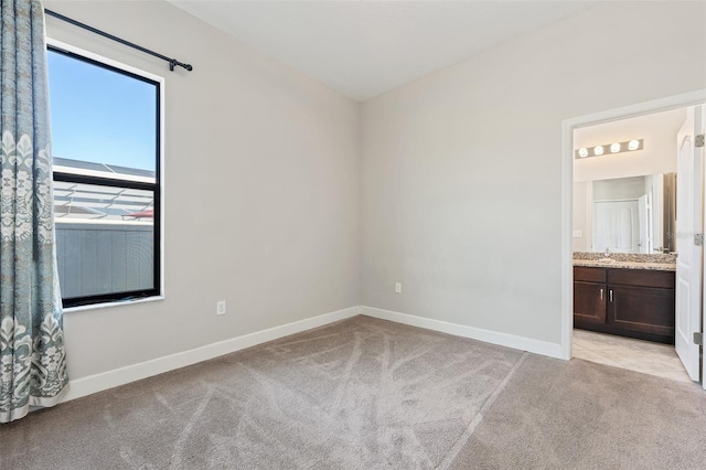 unfurnished bedroom featuring light carpet and connected bathroom