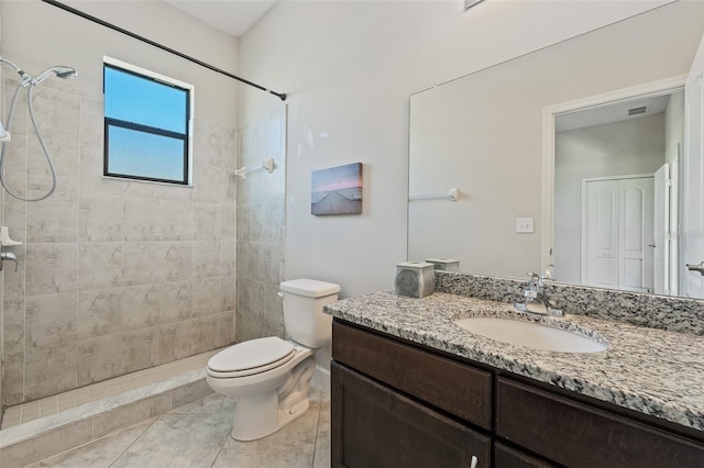 bathroom featuring vanity, tiled shower, tile patterned floors, and toilet