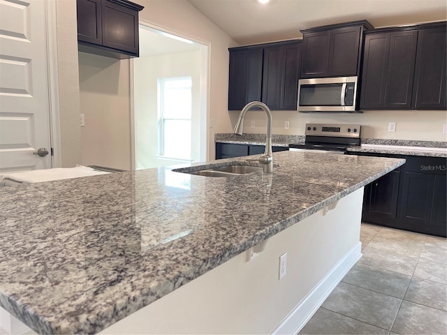 kitchen featuring appliances with stainless steel finishes, sink, stone countertops, vaulted ceiling, and light tile patterned floors