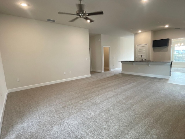 unfurnished living room with light carpet, ceiling fan, and sink