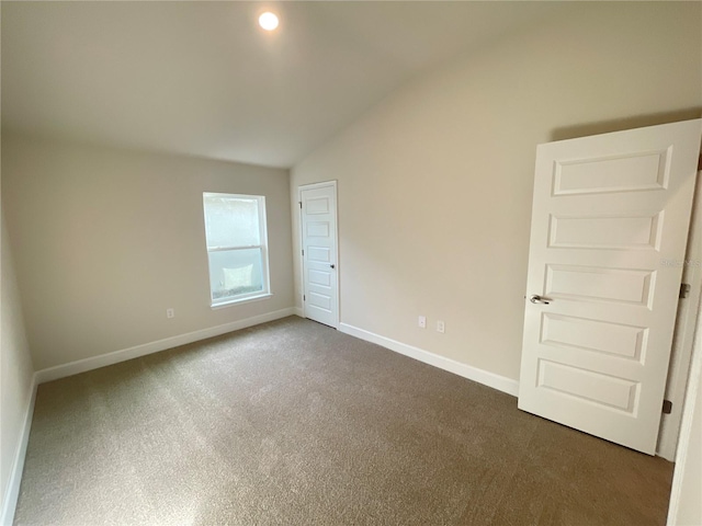 carpeted spare room featuring vaulted ceiling