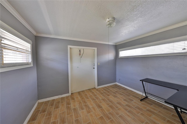 empty room featuring a textured ceiling, ornamental molding, and light wood-type flooring