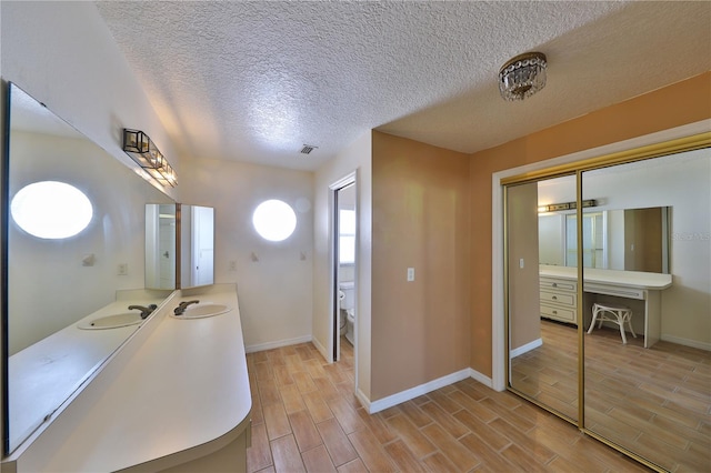 bathroom with a textured ceiling, toilet, and vanity