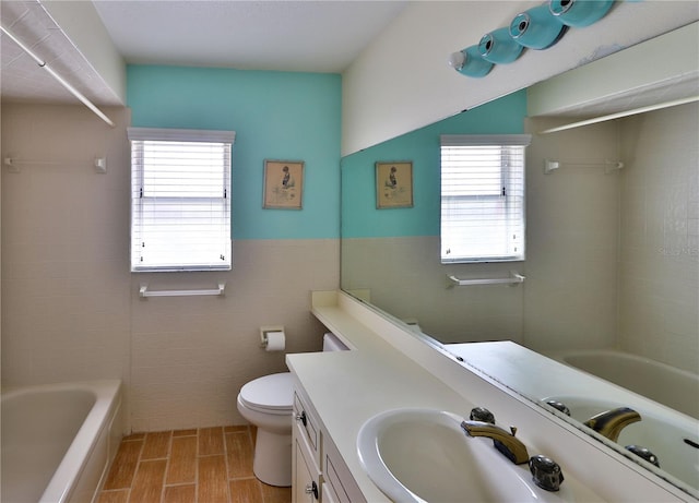 full bathroom featuring tile walls, toilet, vanity, and shower / washtub combination