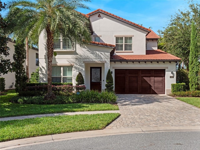 mediterranean / spanish-style house featuring a garage and a front lawn