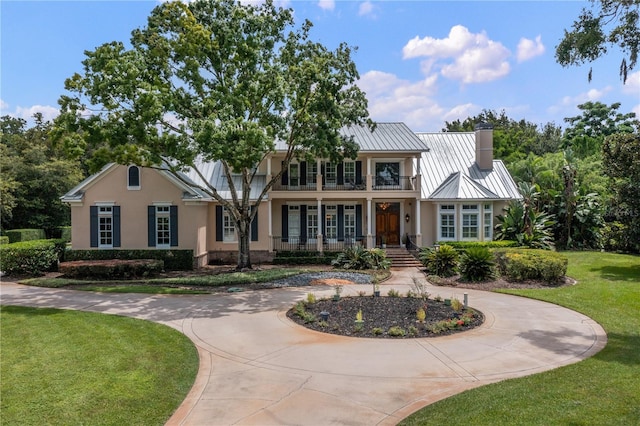 view of front of home with a balcony and a front yard