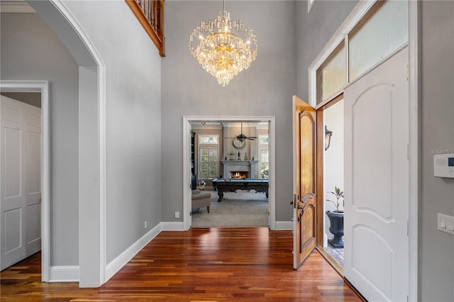 foyer with ceiling fan with notable chandelier, a high ceiling, and hardwood / wood-style floors