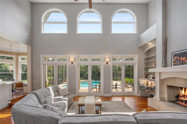 living room featuring a high ceiling, light hardwood / wood-style floors, a fireplace, and french doors