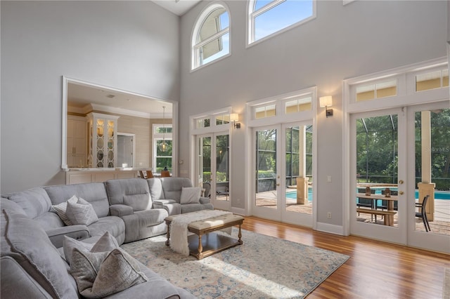 living room featuring a towering ceiling, light hardwood / wood-style floors, and french doors