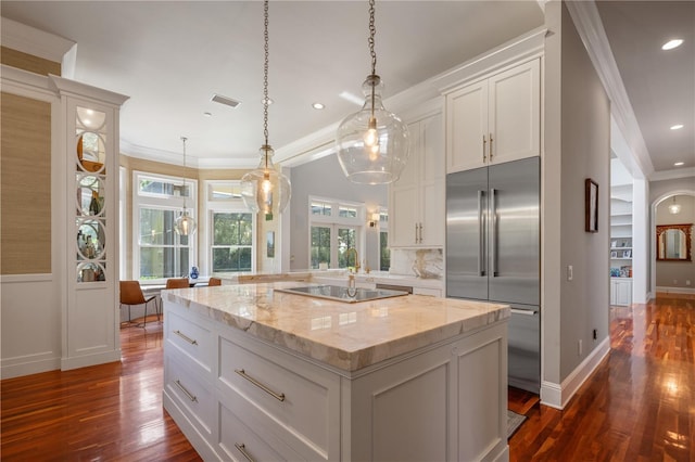 kitchen featuring pendant lighting, a center island, white cabinetry, stainless steel built in refrigerator, and ornamental molding