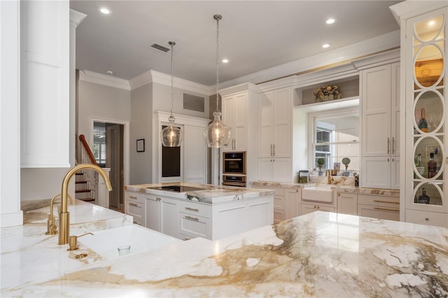 kitchen featuring ornamental molding, pendant lighting, light stone counters, and sink