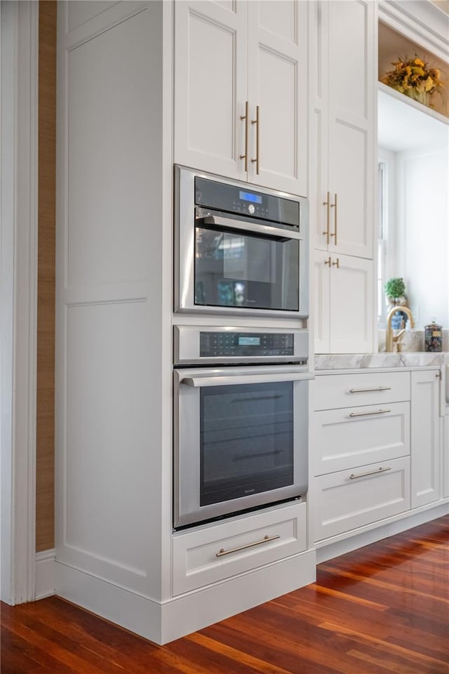 kitchen featuring white cabinetry, double oven, and dark hardwood / wood-style floors