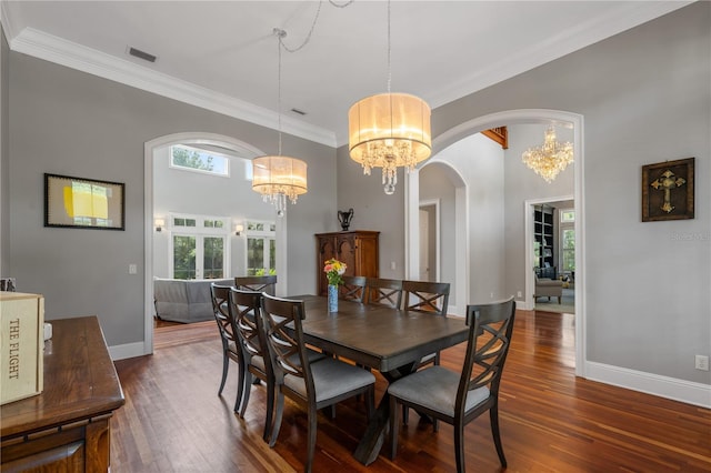 dining area with dark hardwood / wood-style floors, ornamental molding, and an inviting chandelier