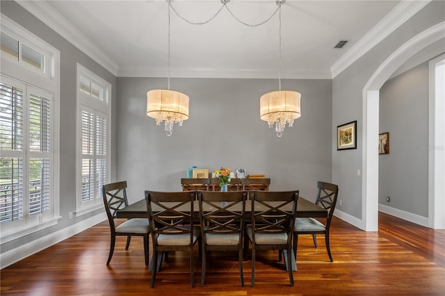 dining area featuring dark hardwood / wood-style flooring, a wealth of natural light, crown molding, and a chandelier